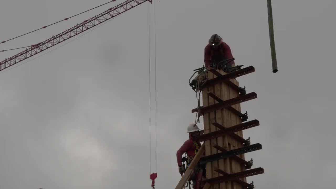 在一个大型商业工地，建筑工人爬上一个混凝土模板，为一根柱子的水泥浇筑做好准备。视频素材