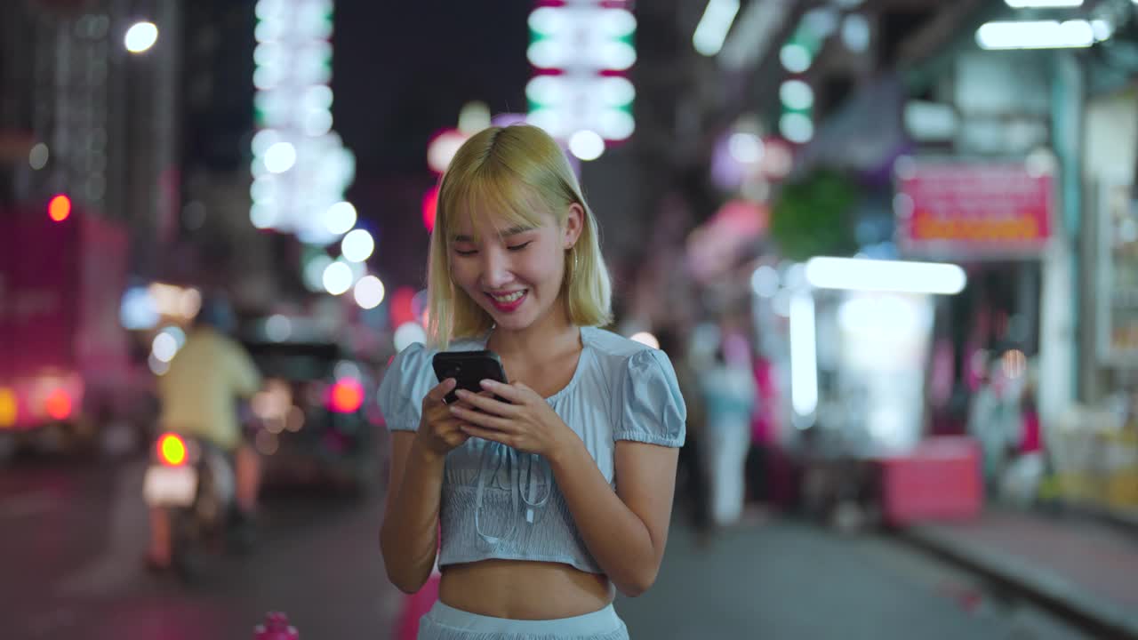 年轻的亚洲人喜欢在晚上用智能手机在曼谷唐人街瑶池游玩视频素材
