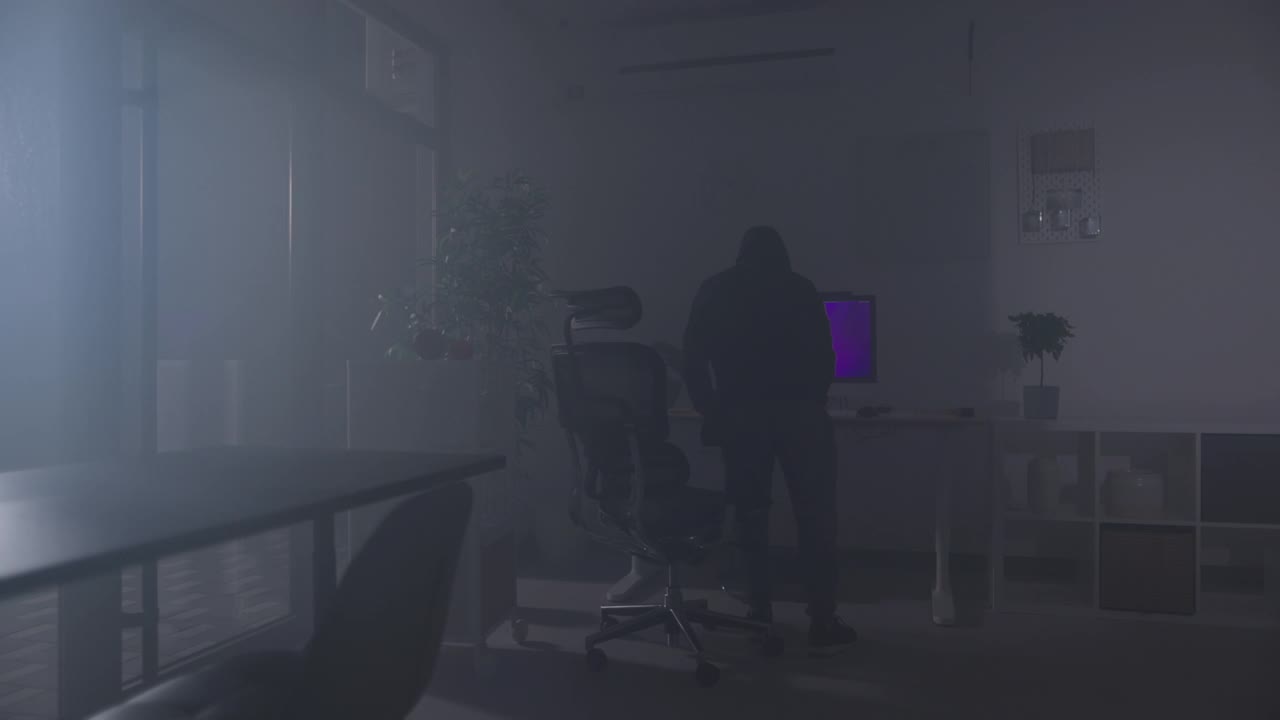 小偷晚上在办公室的电脑上输入密码，试图从电脑中窃取信息视频下载