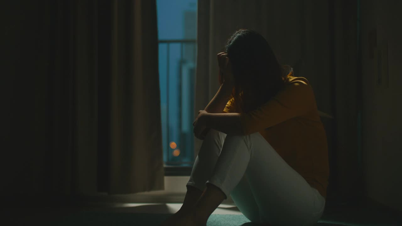 一个抑郁的女人独自坐在公寓房间的地板上视频下载