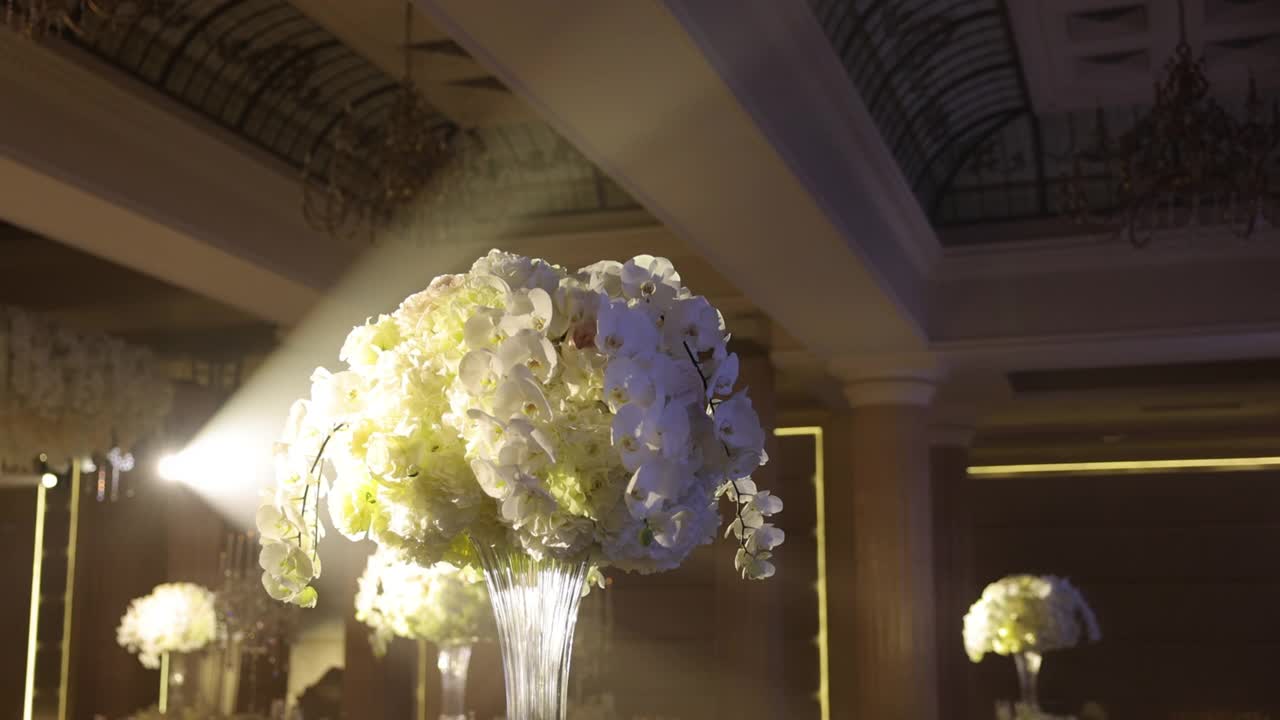 婚礼庆典大厅。餐厅装饰着许多鲜花。花瓶与兰花接近。视频素材