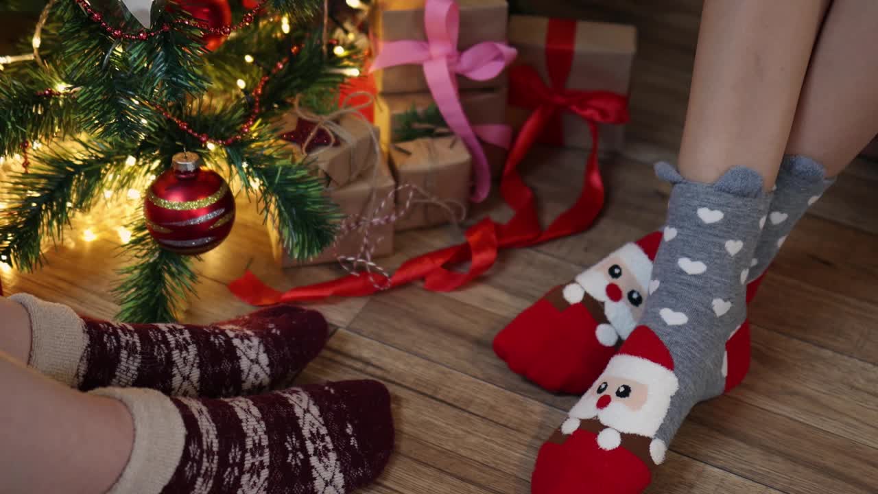 两对女人腿在圣诞袜子坐在装饰枞树礼品盒视频下载