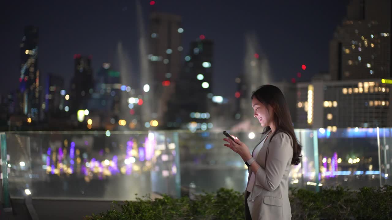 女商人晚上在城市里使用智能手机视频素材