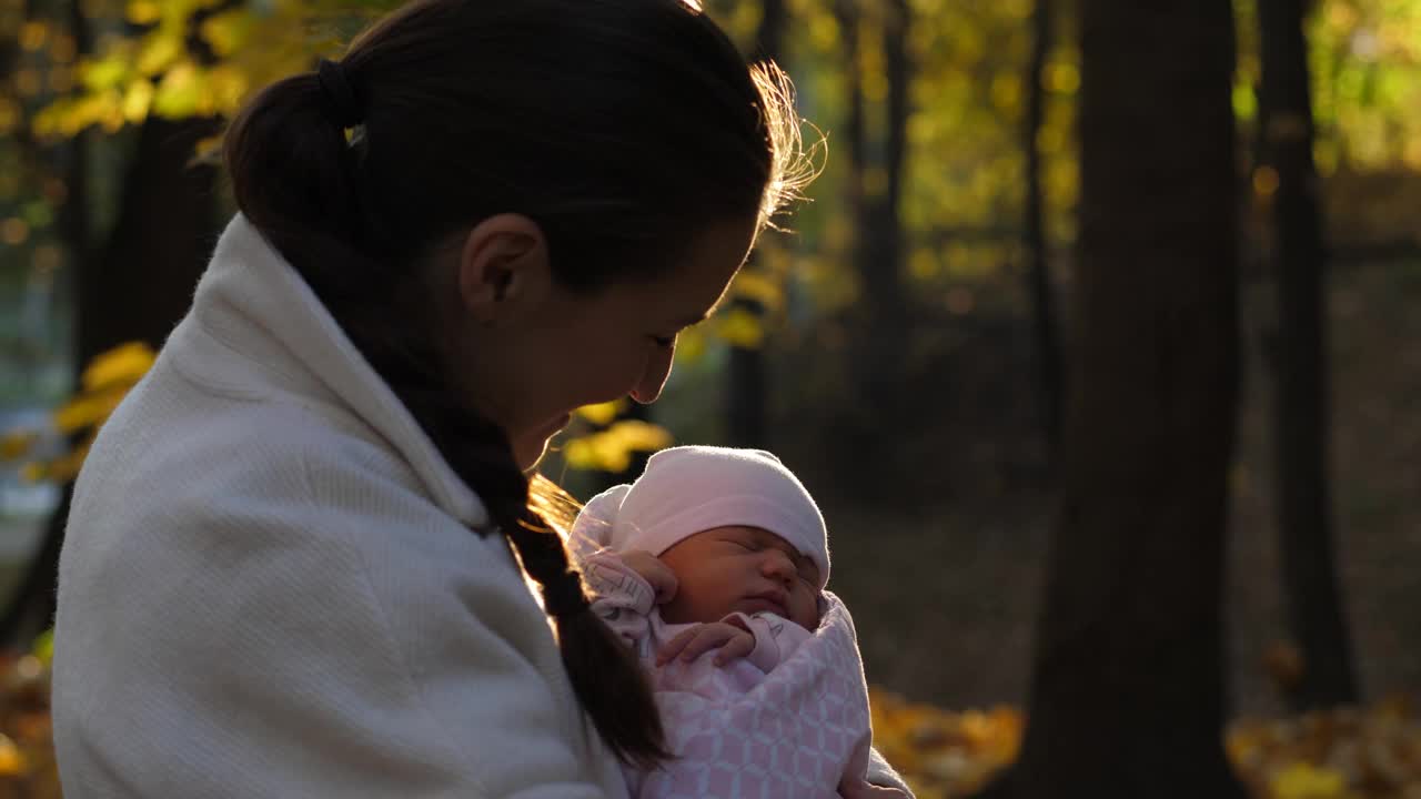 在秋天的公园里，快乐的妈妈抱着她刚出生的孩子视频下载