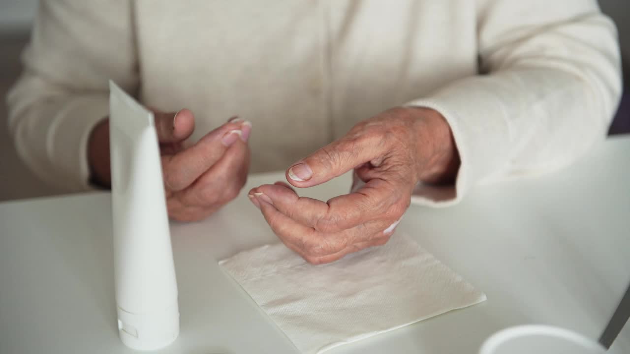 有皱纹的老妇人把保湿霜涂在手上视频素材