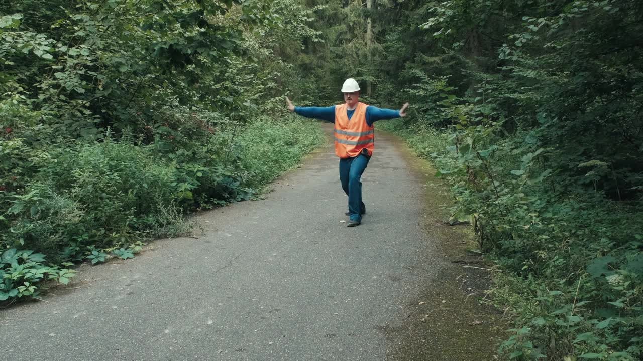 工人穿着工作服用手势表示森林道路上的通道被堵住了视频下载