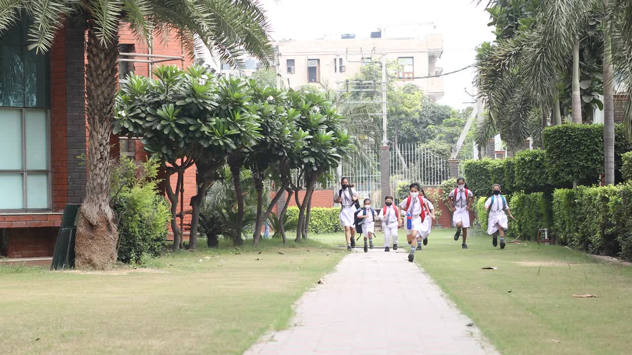孩子们戴着防护口罩跑向学校视频下载