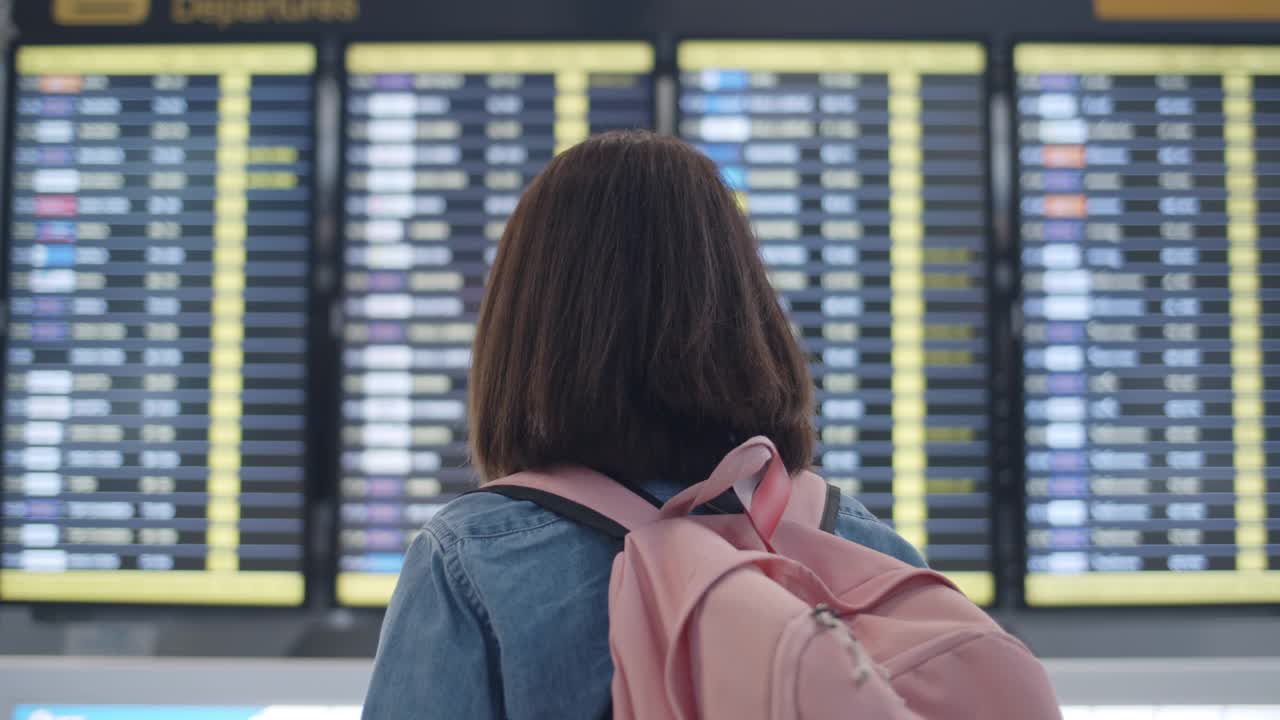 一位女士在国际机场看航班信息牌视频素材