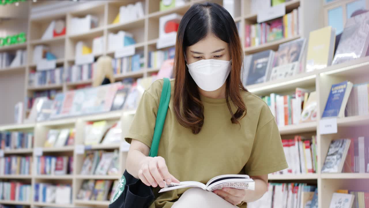 一个亚洲女人在图书馆找书视频素材