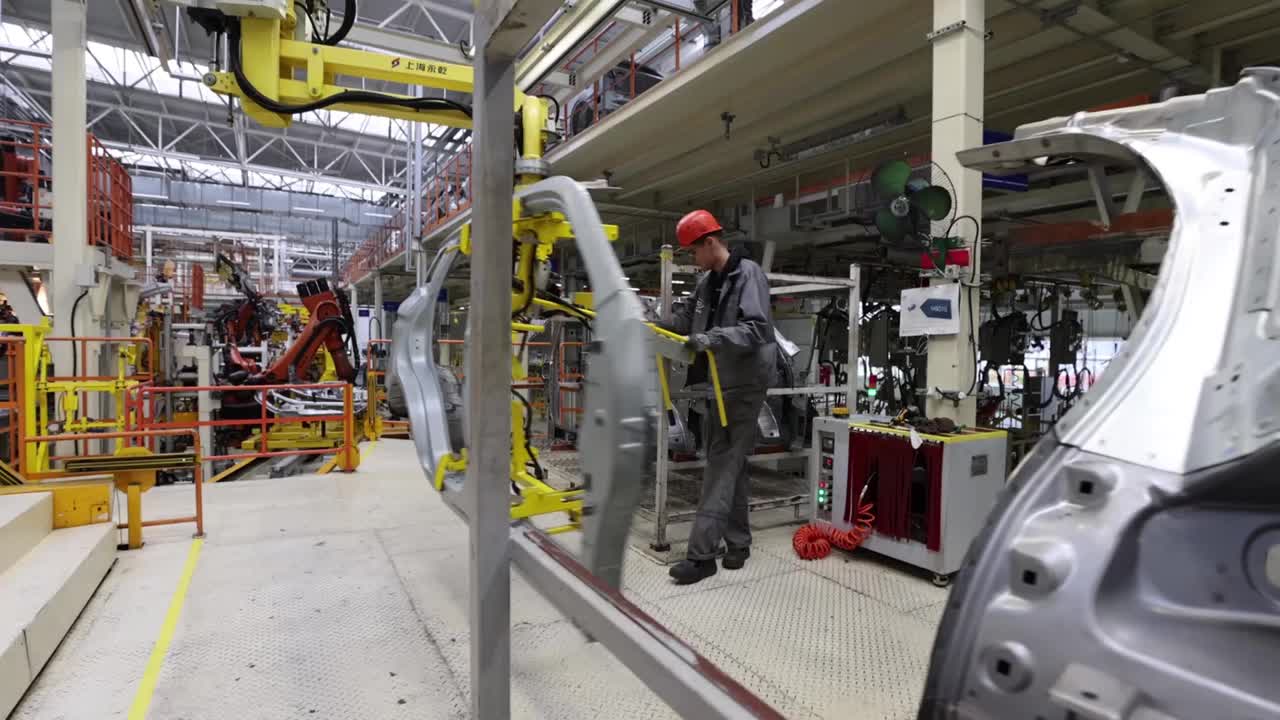 白俄罗斯，鲍里索夫——2021年10月29日:工人将一个汽车部件搬到装配线上，一个现代化的工厂视频素材
