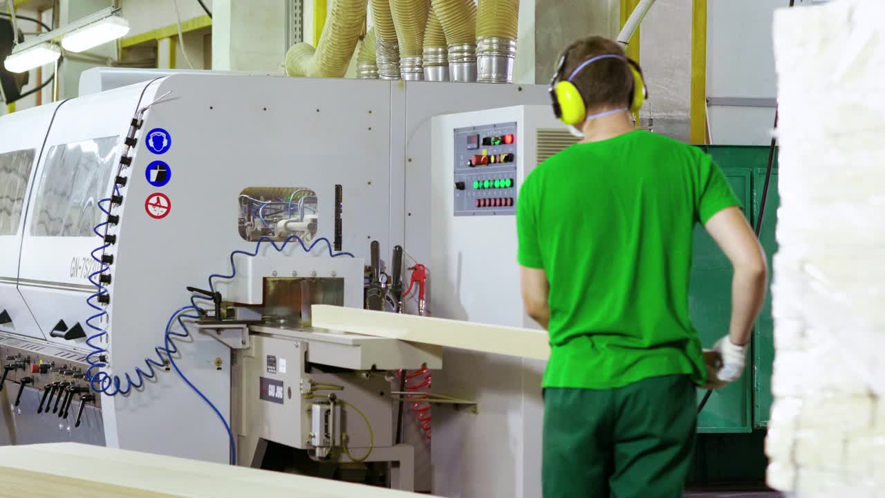 在家具厂里在木工机器上工作的穿制服的人。4 k视频下载