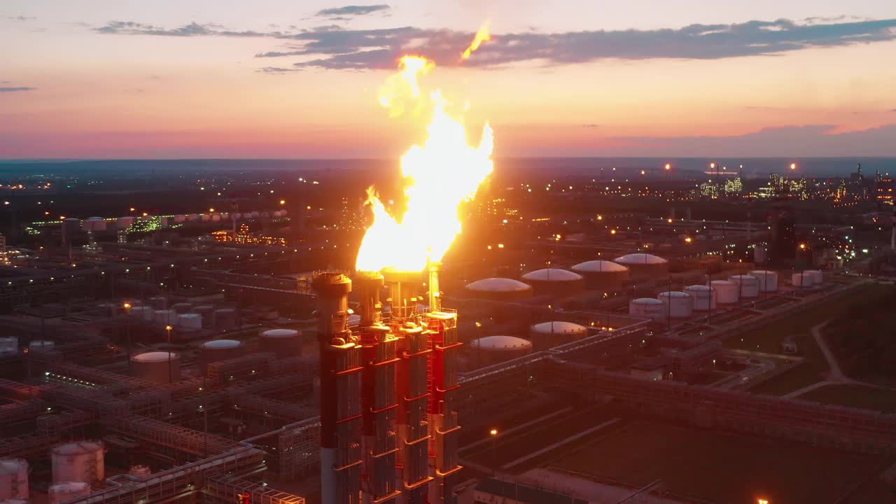 在日落时拍摄的炼油厂天然气火焰和工厂建筑。气候变化的概念。视频素材