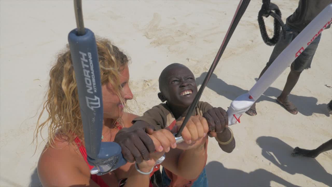 在肯尼亚，一名妇女用风筝板教当地儿童风筝冲浪。——慢动作视频下载