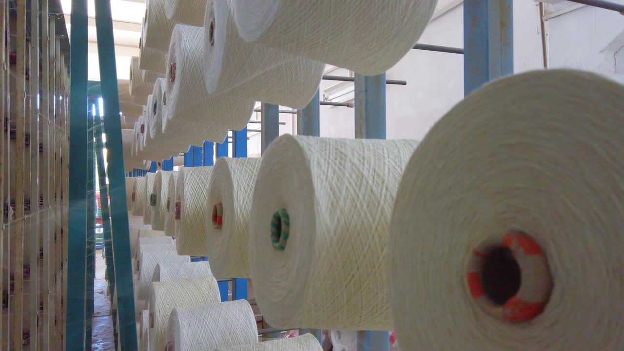 纺织厂工业整经机上按顺序排列的白色线轴、筒管、线筒视频下载