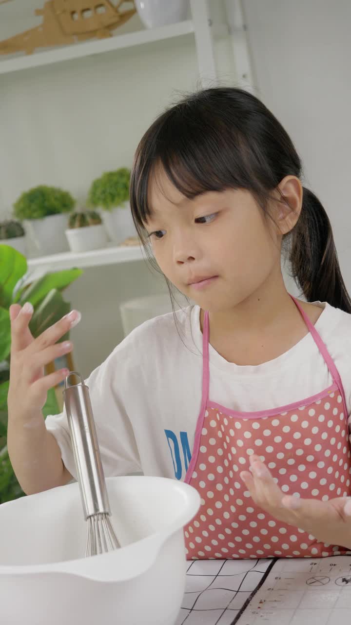 亚洲女孩用面粉把脸涂成白色，在家里和姐姐一起做饼干，生活理念。视频下载