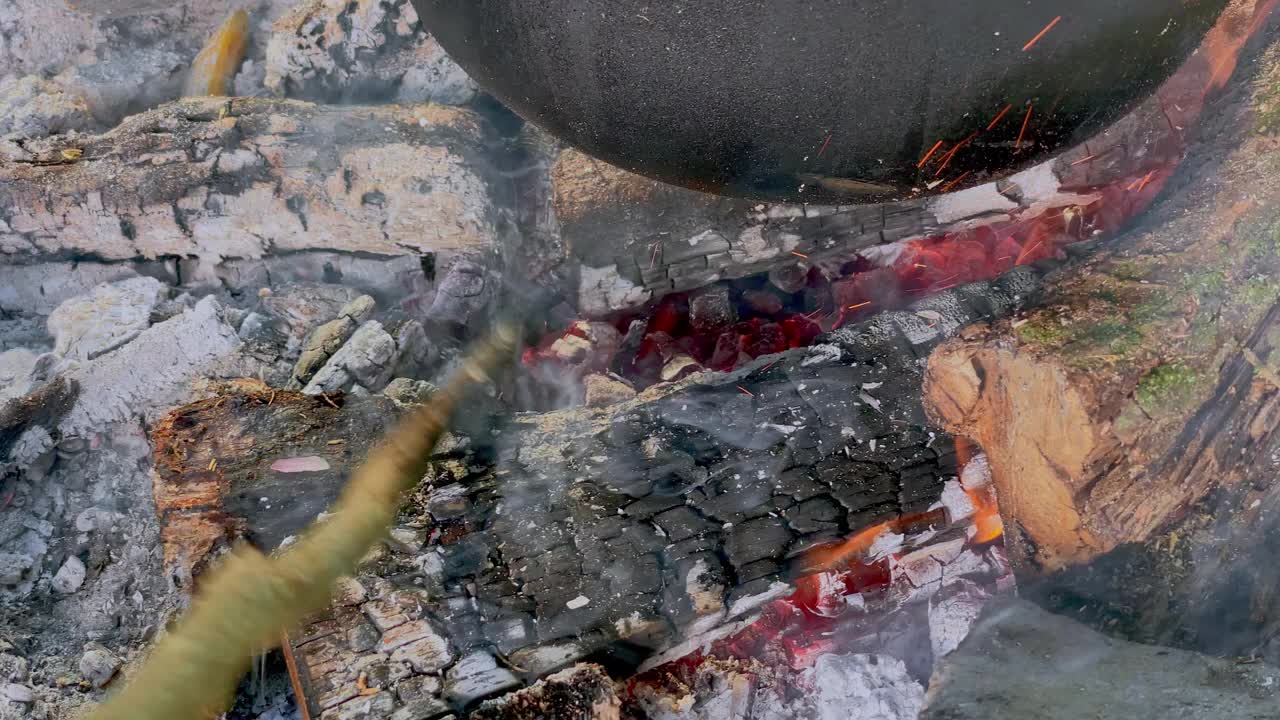 POV在铁锅里炖菜的人，照看营火视频下载