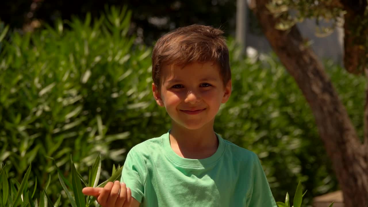 在阳光明媚的夏日，穿着绿色t恤的小男孩用手指数着视频素材