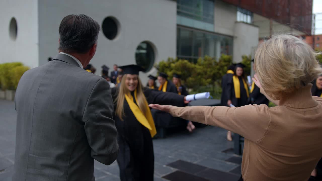 大学毕业典礼后，一个快乐美丽的年轻女子兴奋地拥抱她的父母视频素材
