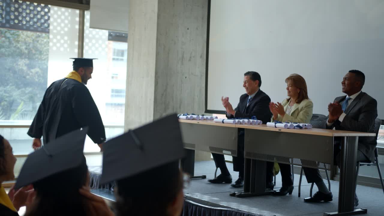 一名自豪的男生在毕业典礼上与老师和院长握手，并领取了毕业证书视频下载