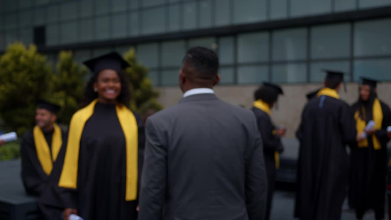 毕业典礼当天，一名快乐的非裔美国研究生抱着父亲，手里拿着毕业证视频下载
