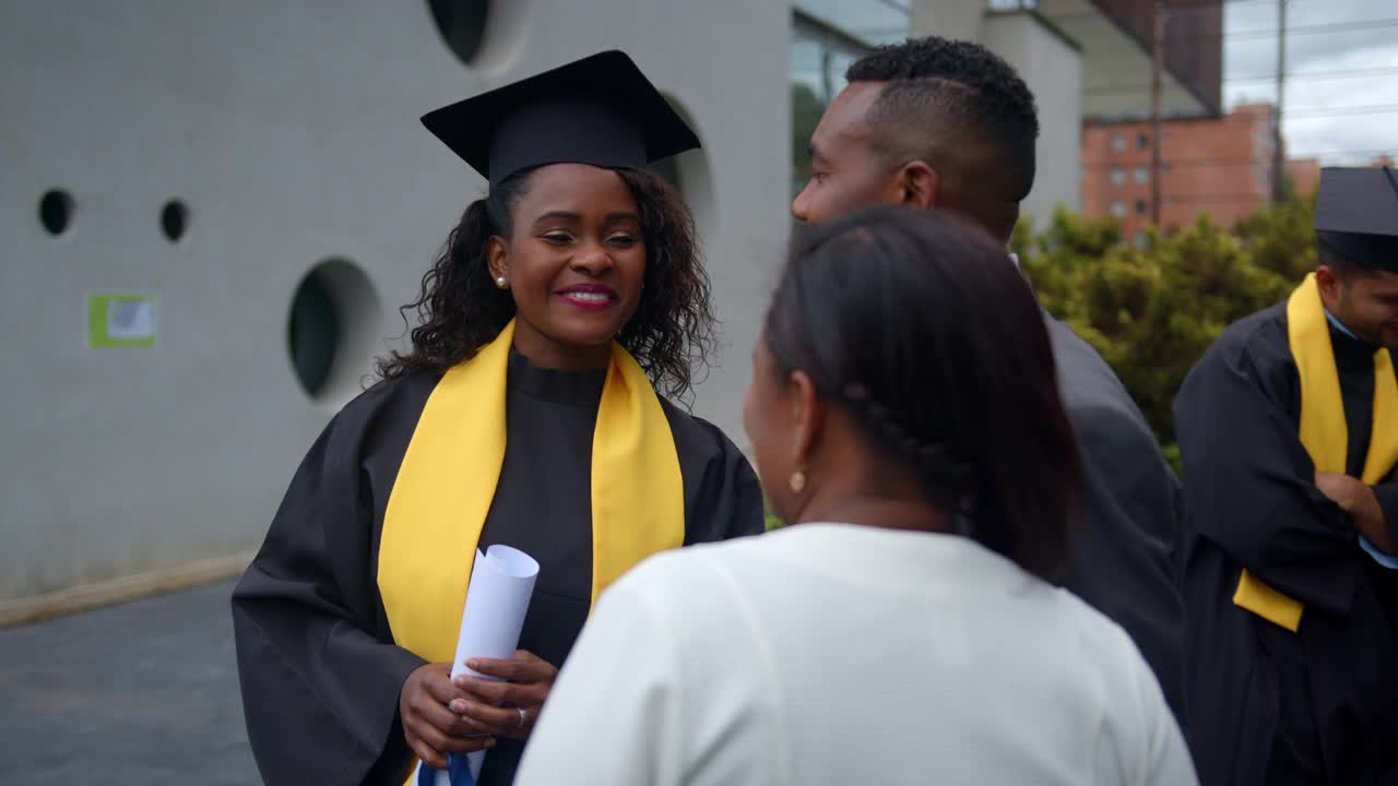自豪的非裔美国父母在毕业典礼后和他们的女儿交谈，看上去非常高兴视频素材