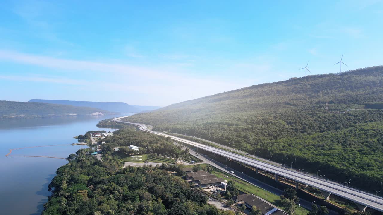 空中无人机超延时延时美丽的高速公路在绿色森林与大坝在公路的一边之间的山。视频素材