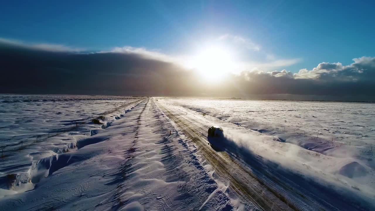 汽车在冰岛路上行驶，白雪山脉和日落乡村，冬天，4K鸟瞰图。视频素材