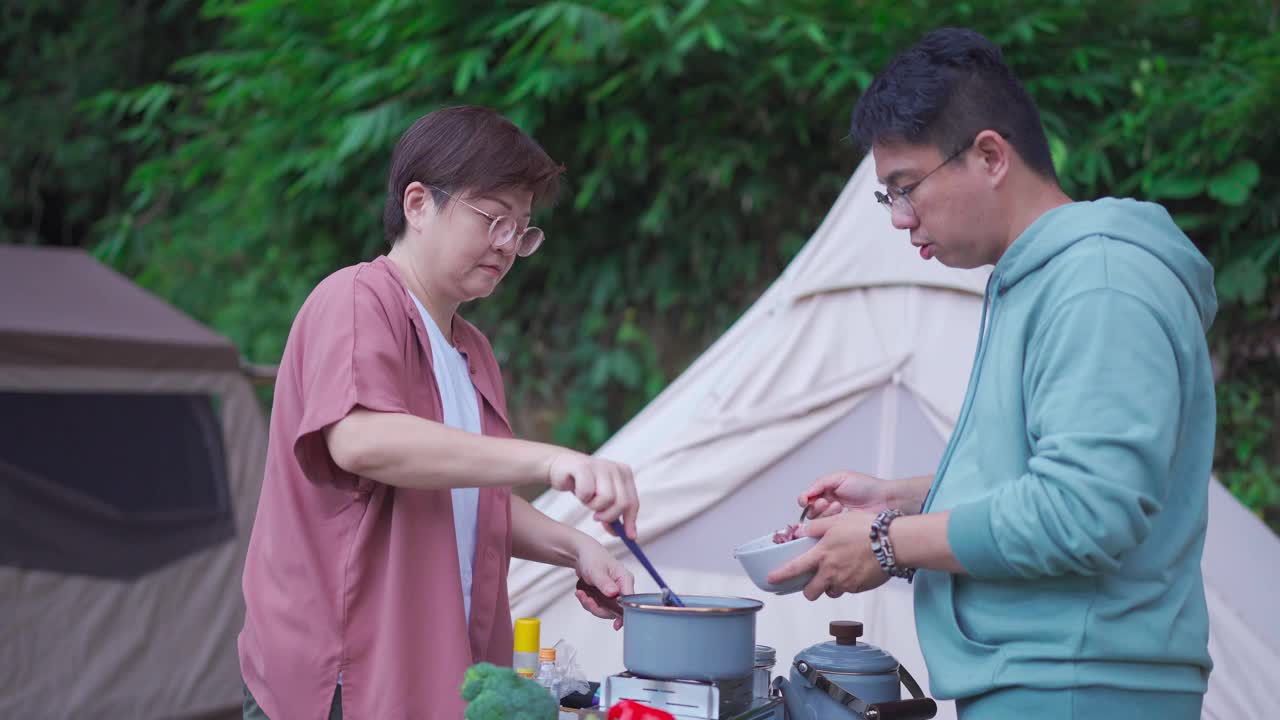 周末早上，亚洲华人夫妇在露营帐篷旁准备早餐视频素材