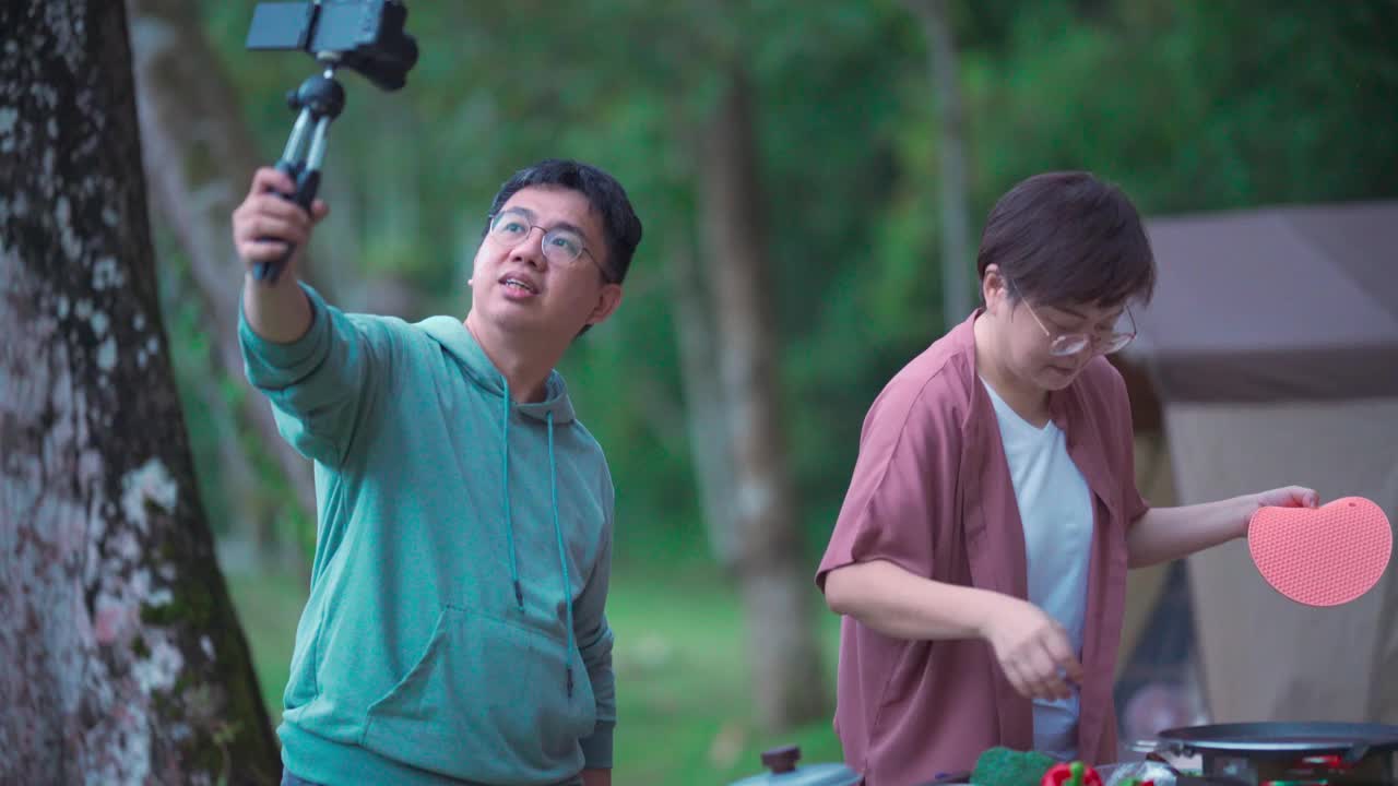 亚洲华人中年夫妇享受烹饪时间，晚上在露营帐篷旁拍视频准备食物视频下载