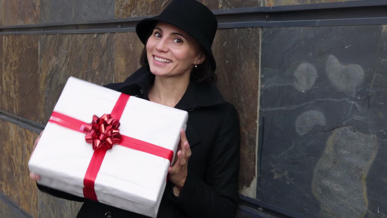 特写的快乐可爱的女人在帽子显示她的圣诞礼物。外视频下载