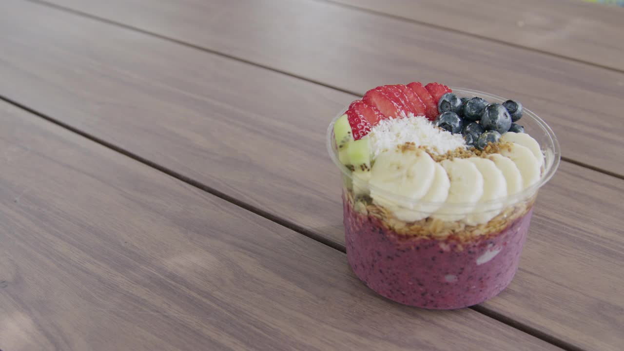 中等手持拍摄的健康巴西莓食品碗在户外木桌与复制空间夏天视频下载