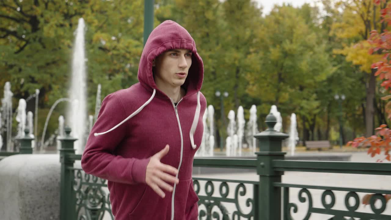 戴兜帽的男人在秋天公园跑步视频下载
