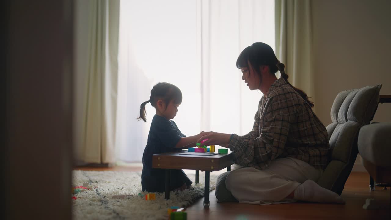 小女孩和她的妈妈在家里的客厅里用彩色的粘土做形状视频下载