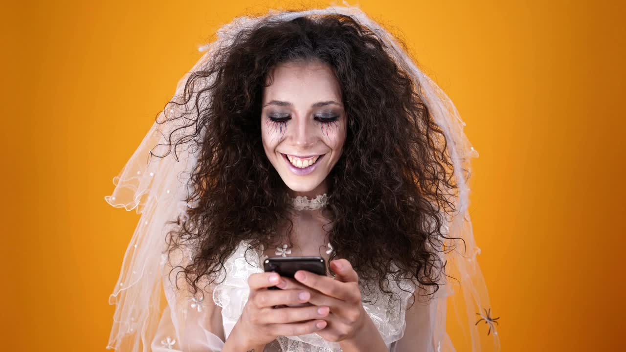 万圣节快乐死去的新娘穿着婚纱，用智能手机化妆视频素材