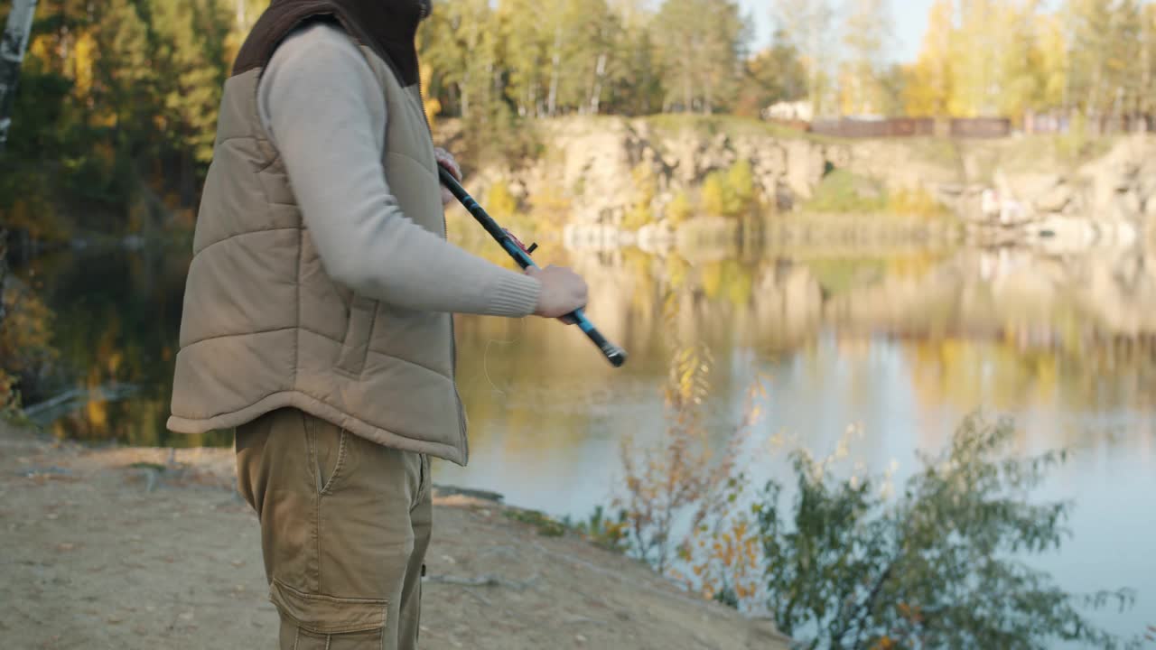 男性手在河边用现代钓竿捕鱼的低镜头视频素材