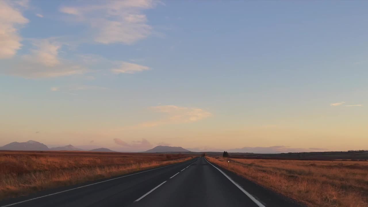 在美丽的晨光中行驶在冰岛笔直的道路上。视频下载