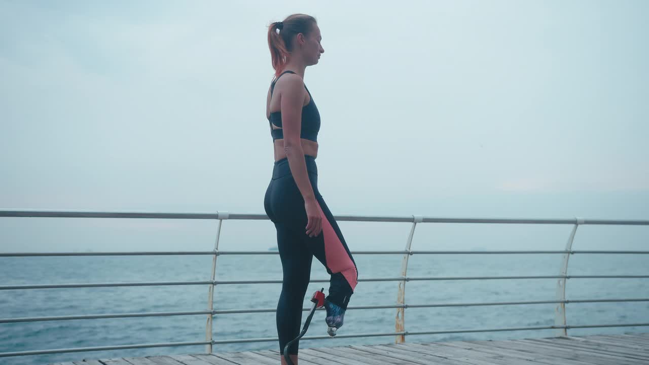 戴着生物假肢的女士站在健康的腿上练习瑜伽视频素材