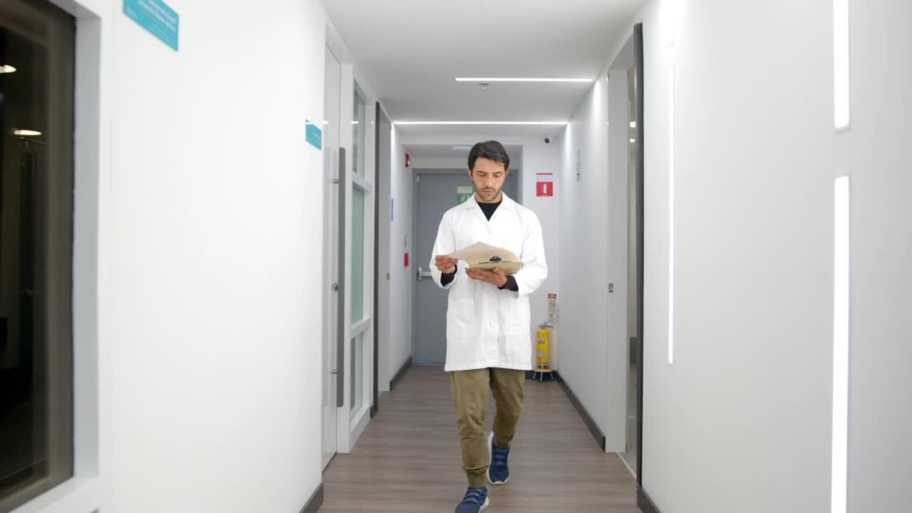 男医生一边看病历一边走在医院的走廊上视频下载