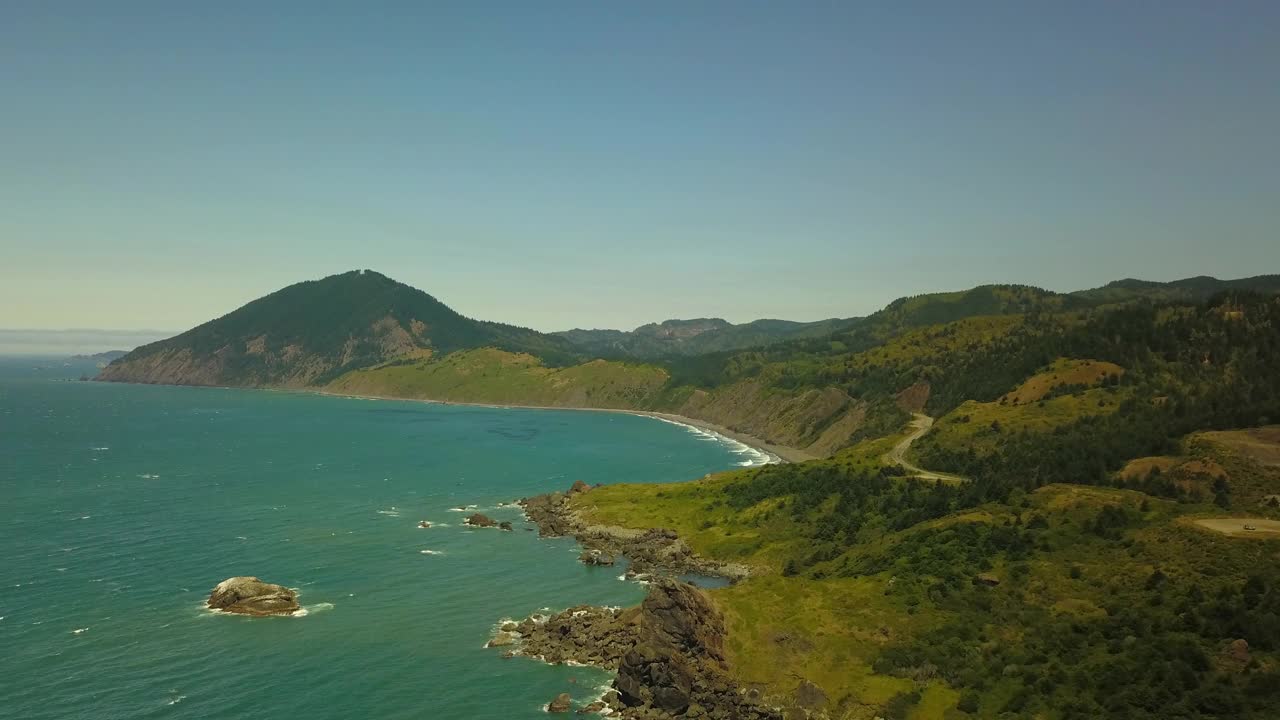 航拍拍摄的海浪冲击海岸线在阳光明媚的日子，无人机飞越大海反对蓝天-俄勒冈海岸，俄勒冈视频下载