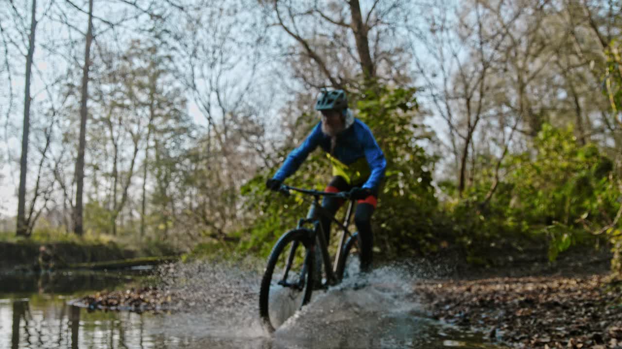 山地摩托车手穿越森林中的小溪的时间扭曲效应视频下载