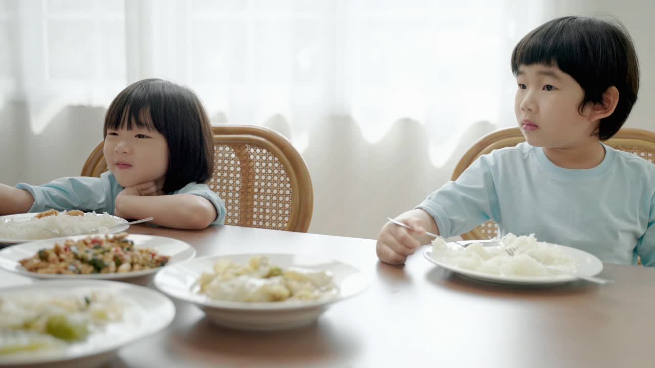 亚洲男孩学着自己在餐桌上吃饭视频素材