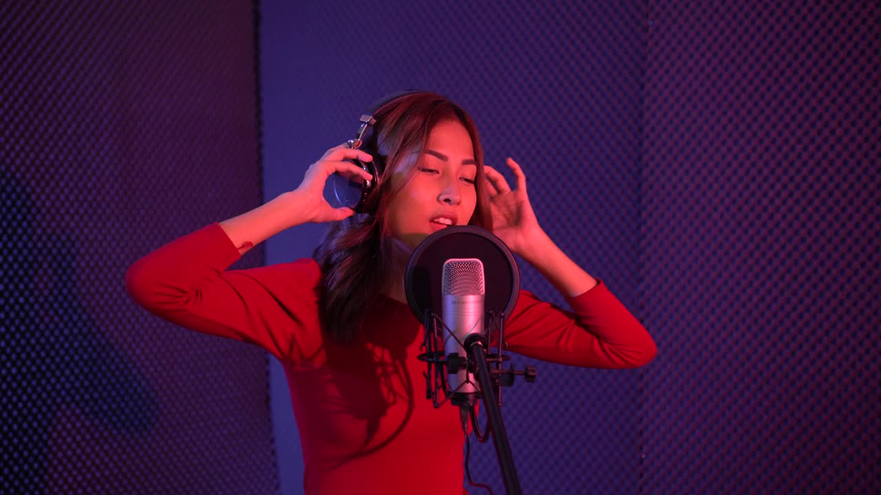 一位美丽的亚洲女歌手正在录音室练习唱歌。视频下载