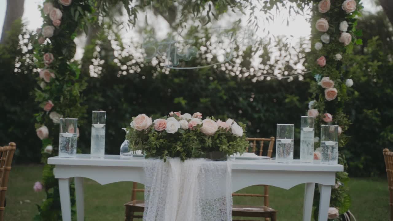 令人惊叹的婚礼布置在花园，白色桌布和木制椅子的桌子。美丽的节日气氛。花园里到处都是粉红色和白色的玫瑰。视频素材