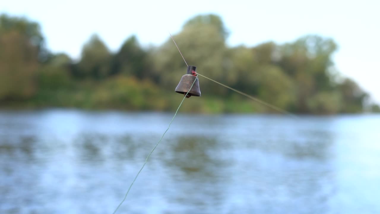 一个挂在钓鱼线上的旧铜铃的特写镜头。铃响是咬人的信号。鱼咬人。传统的捕鱼装置。活动周末，男人的爱好视频素材