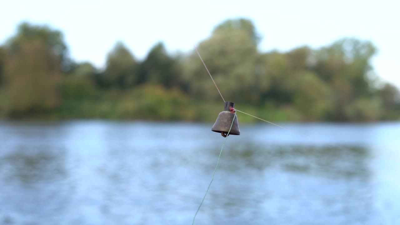一个挂在钓鱼线上的旧铜铃的特写镜头。钟从绳子上掉了下来。鱼咬人。传统的捕鱼装置。活动周末，男人的爱好视频素材