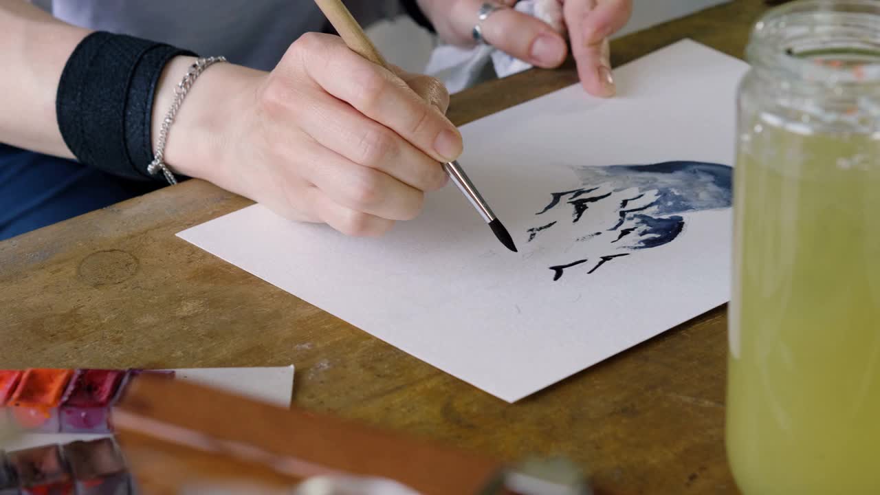 特写的艺术家的手画鸟在蓝色的心水彩画。4 k视频下载
