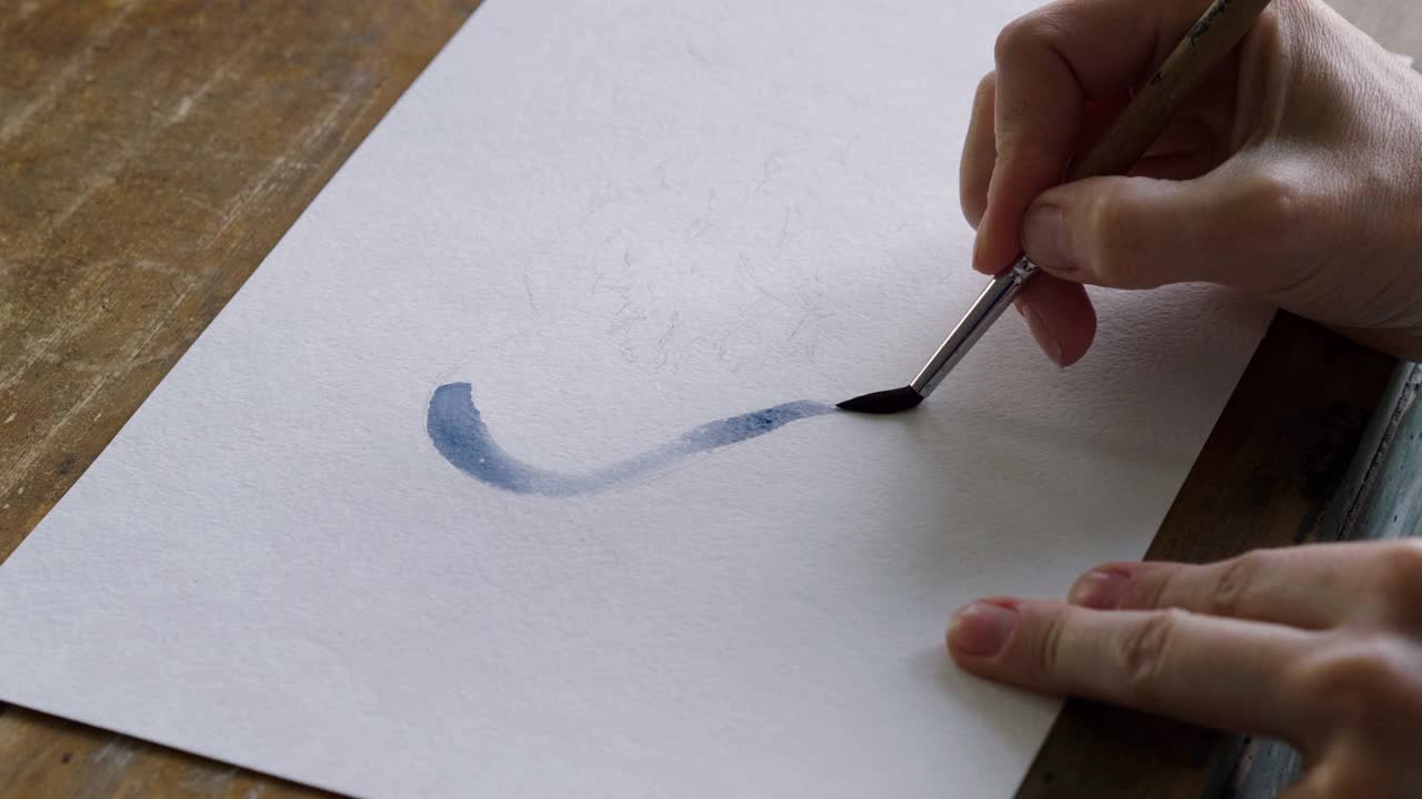 在艺术工作室里，女性的手用毛笔画了一颗蓝色的心。4 k视频下载