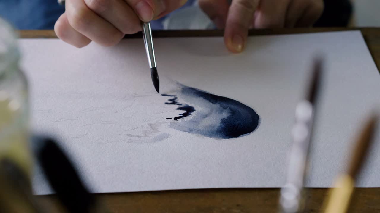 在艺术工作室里，手用画笔在水彩画一个蓝色的心。4 k视频下载