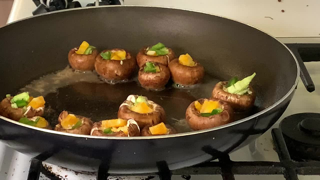 烹饪在煤气炉上的黑色煎锅中准备的墨西哥胡椒和奶酪蘑菇视频下载
