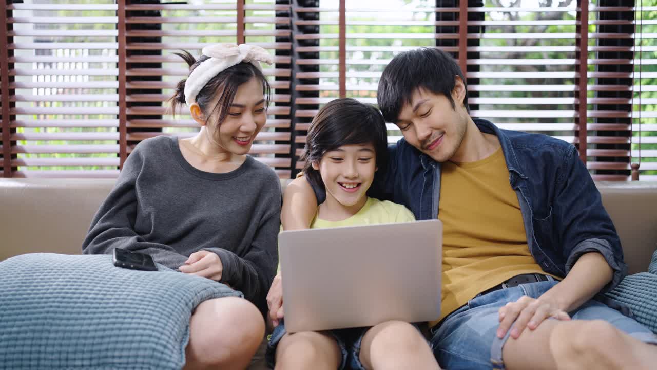 家人在笔记本电脑上对着镜头微笑交谈。幸福的家庭在家里讲视频电话。视频素材